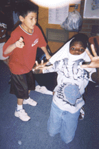 The photograph shows two students dramatizing a dinosaur and a volcano.