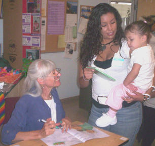 This is a photograph of Judi signing a poster for a Project LIFT mother and child.